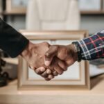 Close-up of a handshake between two professionals in an office environment.